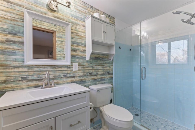 bathroom with toilet, wallpapered walls, vanity, and a stall shower