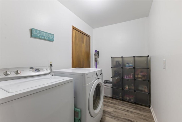 washroom with laundry area, baseboards, washer and clothes dryer, and dark wood-type flooring