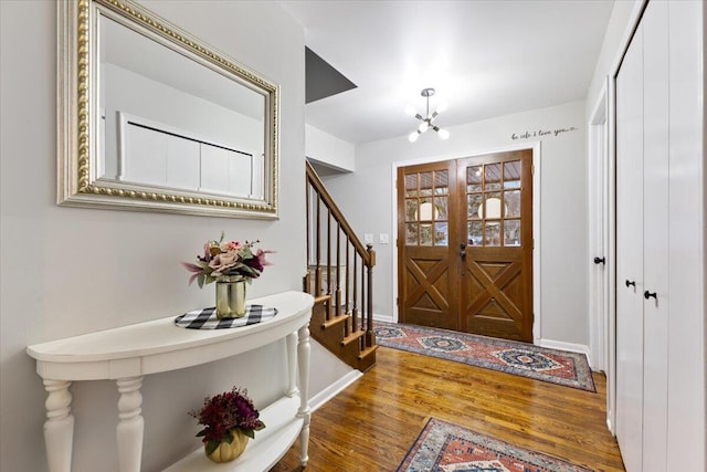 foyer entrance with an inviting chandelier, baseboards, stairway, and wood finished floors