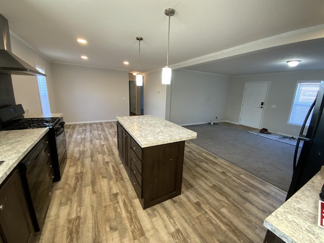 kitchen with a center island, decorative light fixtures, wall chimney exhaust hood, light countertops, and black appliances