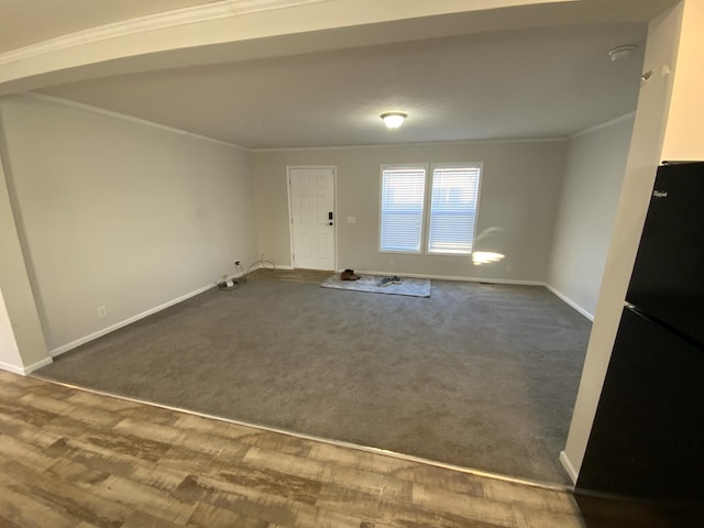 empty room featuring dark wood finished floors, baseboards, dark colored carpet, and crown molding