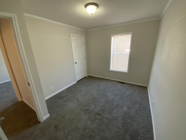 unfurnished bedroom with baseboards, visible vents, dark carpet, and crown molding