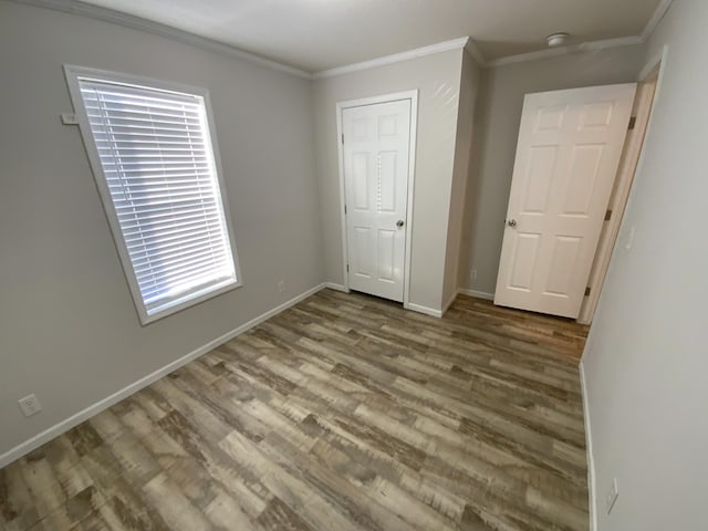 unfurnished bedroom featuring baseboards, wood finished floors, and crown molding