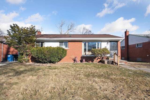 view of front of property featuring a front yard, brick siding, and a chimney