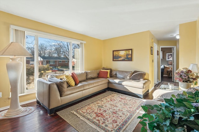 living room featuring ornate columns, dark wood finished floors, and baseboards