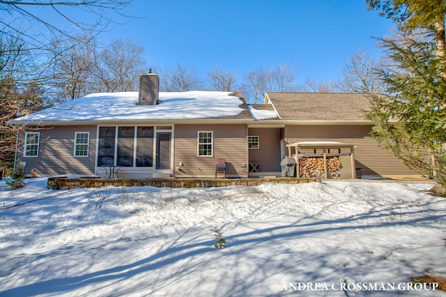 snow covered back of property featuring a chimney