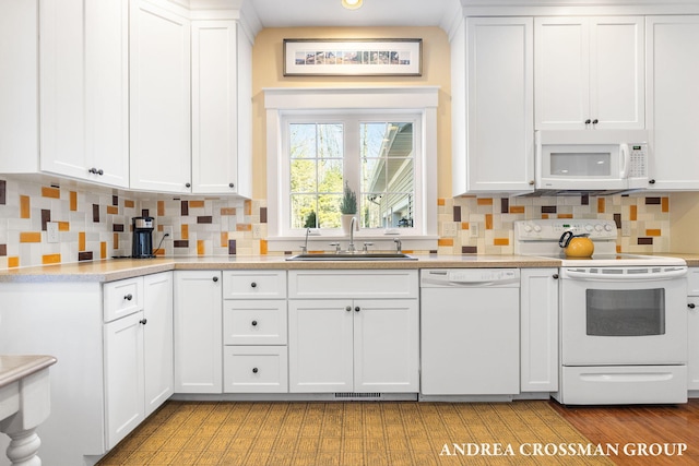 kitchen featuring light countertops, white appliances, a sink, and white cabinets