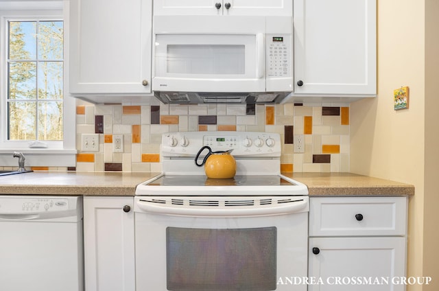 kitchen featuring white appliances, a sink, white cabinetry, light countertops, and decorative backsplash