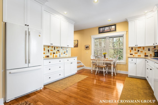 kitchen featuring light countertops, decorative backsplash, freestanding refrigerator, and white cabinets