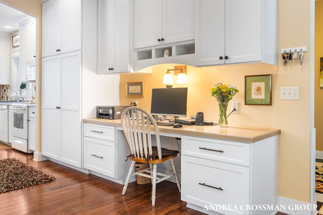 office space with a sink, built in desk, arched walkways, and dark wood finished floors