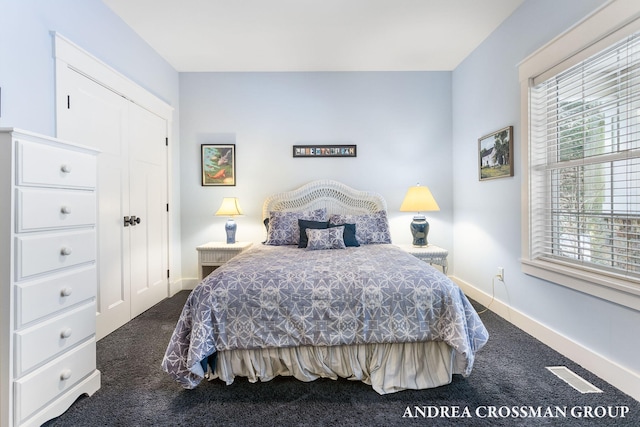 bedroom featuring dark colored carpet, multiple windows, and baseboards