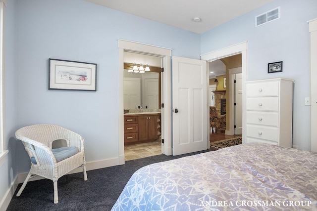 bedroom with light carpet, ensuite bathroom, visible vents, and baseboards