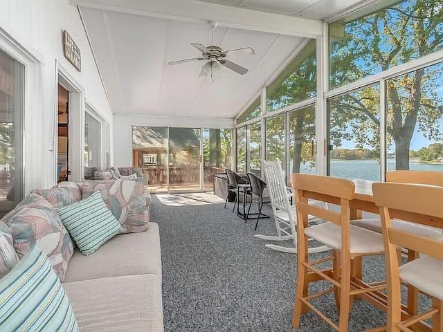 sunroom with a water view, plenty of natural light, ceiling fan, and lofted ceiling with beams