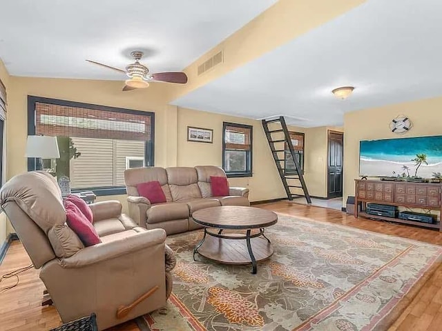 living room with baseboards, visible vents, a ceiling fan, light wood-style flooring, and stairway