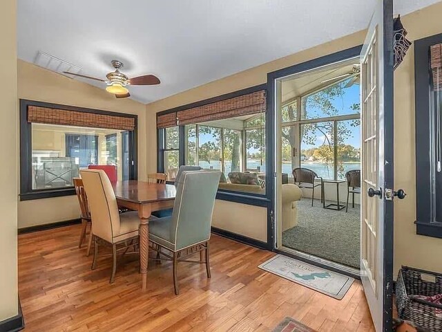 dining area featuring a water view, wood finished floors, and a healthy amount of sunlight