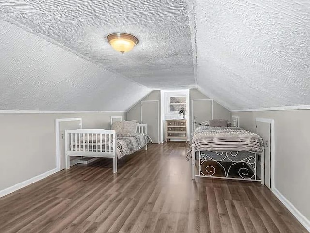 unfurnished bedroom with dark wood-style flooring, vaulted ceiling, a textured ceiling, and baseboards