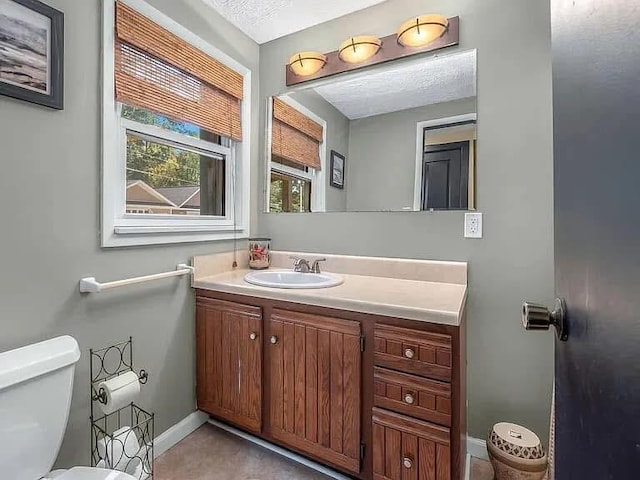 half bath featuring toilet, vanity, and baseboards