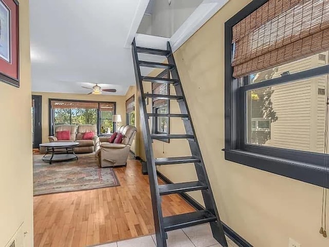 doorway featuring light wood-type flooring, a ceiling fan, and baseboards