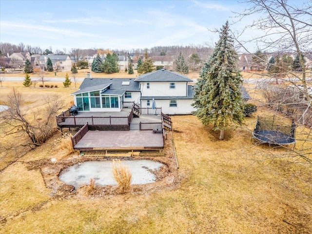 rear view of house with a sunroom, a trampoline, and a deck