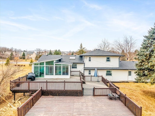 rear view of house featuring a sunroom, a lawn, and a deck