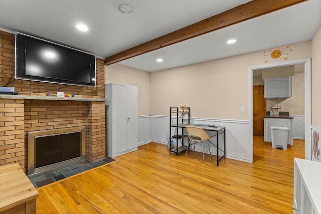 living room featuring a fireplace, wainscoting, wood finished floors, and beam ceiling