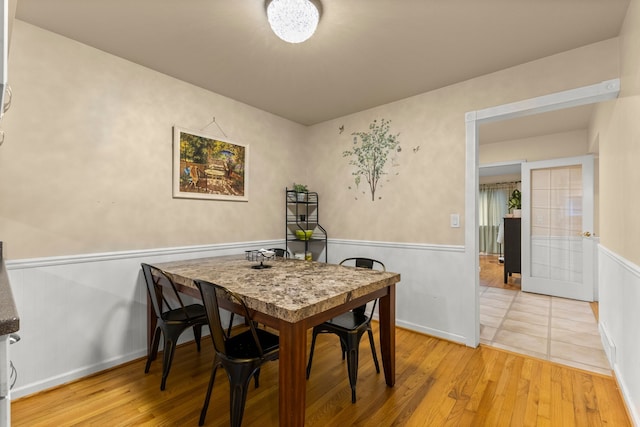 dining area with a wainscoted wall and light wood finished floors