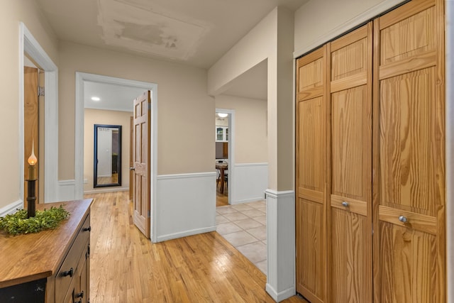 corridor with a wainscoted wall and light wood-style flooring