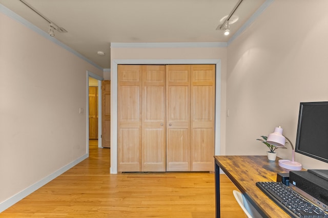 unfurnished office with baseboards, track lighting, light wood-type flooring, and crown molding