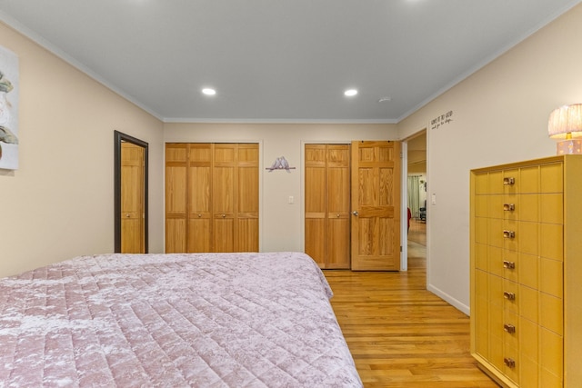 bedroom featuring multiple closets, recessed lighting, crown molding, and light wood-style floors