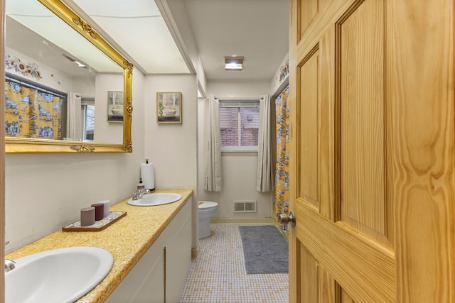 bathroom featuring visible vents, a sink, toilet, and double vanity