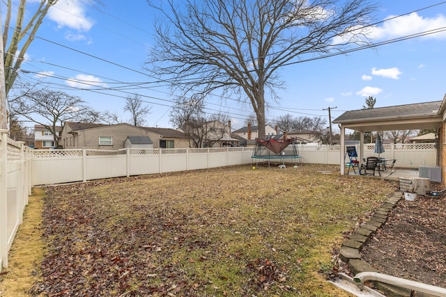 view of yard featuring a trampoline, a patio area, and a fenced backyard