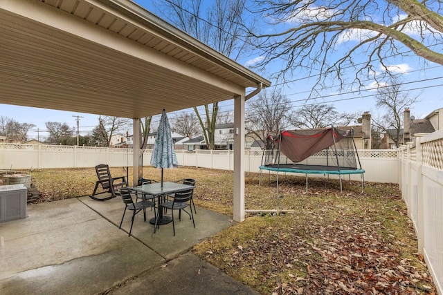 view of patio featuring a fenced backyard, a trampoline, and outdoor dining area