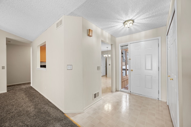 foyer entrance featuring baseboards, visible vents, a chandelier, and a textured ceiling