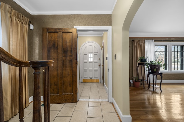 foyer with baseboards, arched walkways, and ornamental molding