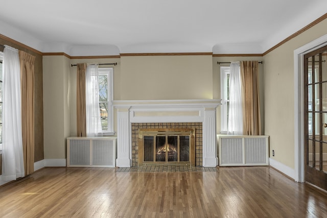 unfurnished living room featuring baseboards, wood finished floors, a tile fireplace, and radiator