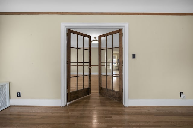 spare room with radiator heating unit, wood finished floors, and baseboards