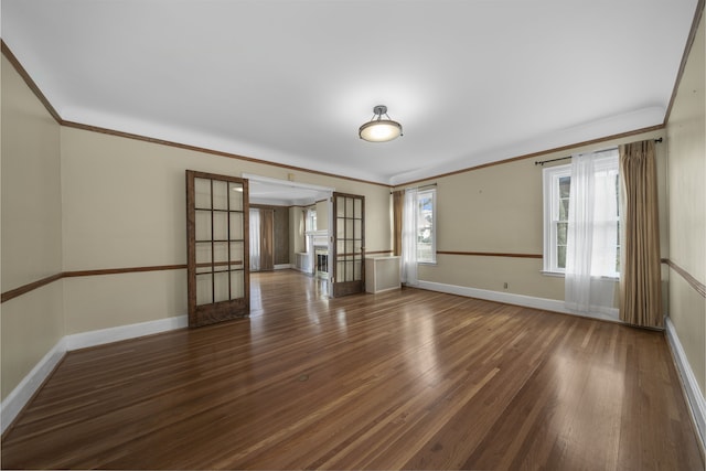 spare room with baseboards, wood finished floors, and crown molding