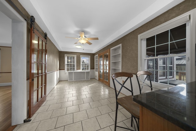 sunroom with a ceiling fan, french doors, and a barn door