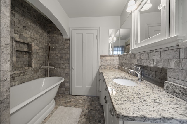 bathroom with a soaking tub, tasteful backsplash, and vanity