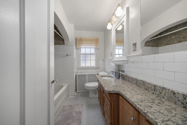 bathroom with tile walls, toilet, a bathing tub, vanity, and tile patterned flooring