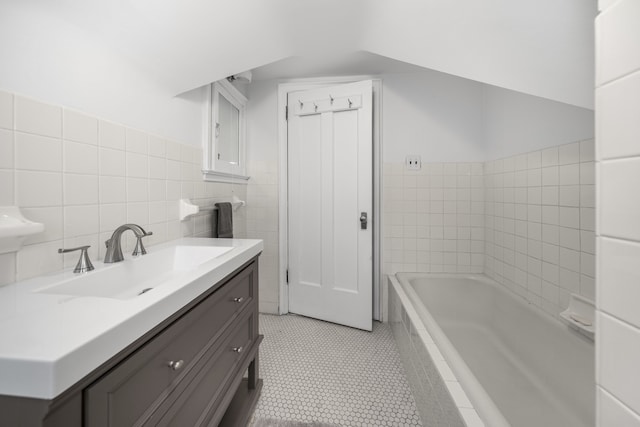 full bath featuring a relaxing tiled tub, tile walls, vanity, and tile patterned floors