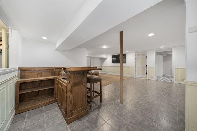 bar with tile patterned floors, recessed lighting, and wainscoting