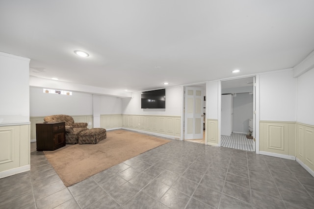 finished basement with recessed lighting and a wainscoted wall