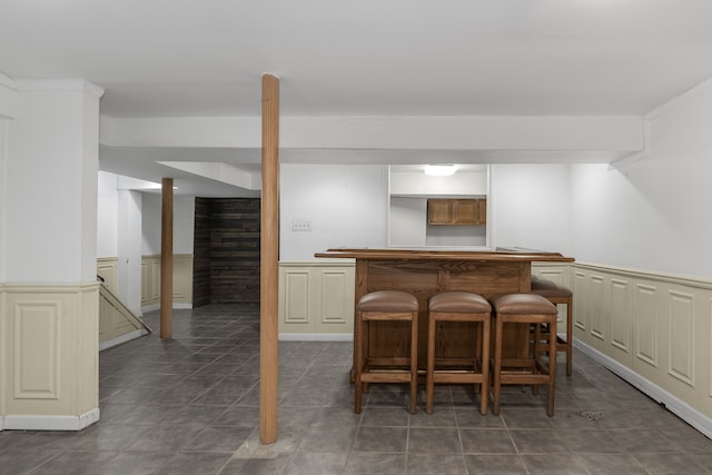 bar featuring a dry bar, tile patterned flooring, and wainscoting