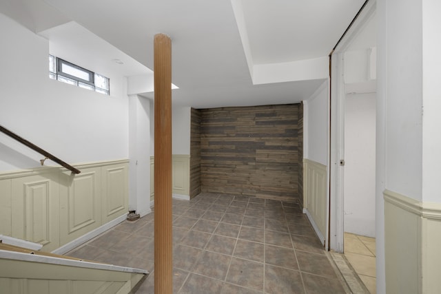 interior space with an accent wall, a wainscoted wall, wood walls, and tile patterned floors