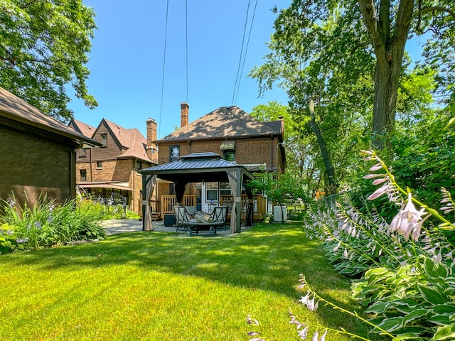 rear view of property with brick siding, fence, a gazebo, a yard, and a patio area