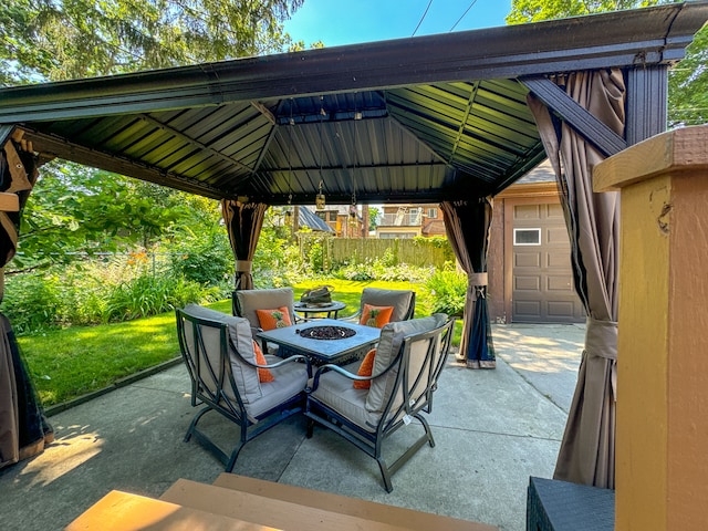 view of patio / terrace featuring a garage, an outdoor fire pit, fence, and a gazebo