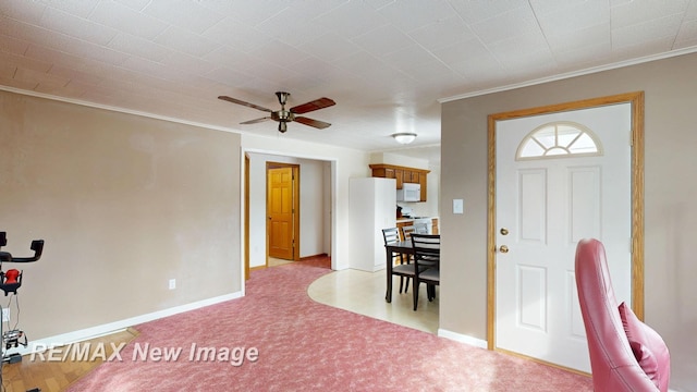 foyer featuring light carpet, baseboards, and crown molding