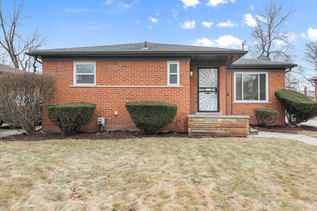 bungalow featuring brick siding, a front lawn, and roof with shingles