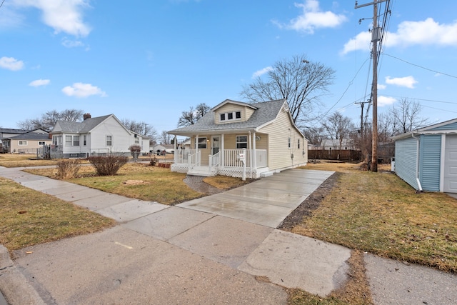 bungalow-style home featuring concrete driveway, a porch, roof with shingles, fence, and a front lawn